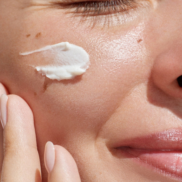 Close-up of a woman applying Retinol super cream to her face