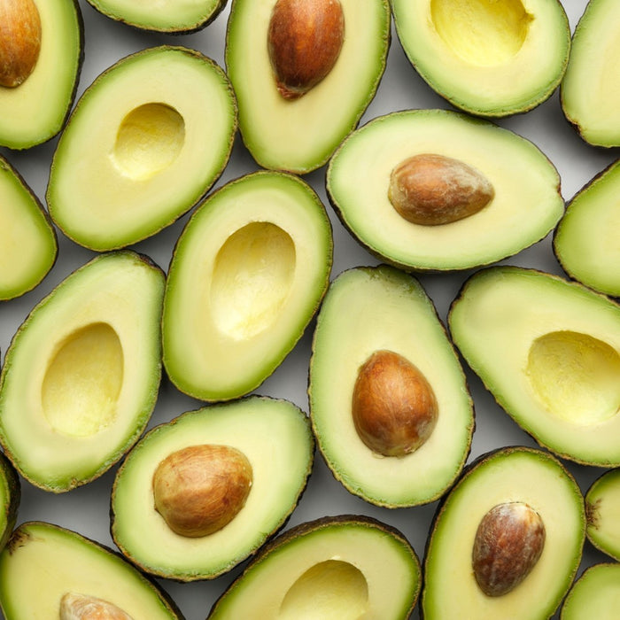 Pattern of halved avocados with seeds on a gray background representing Vitamin E