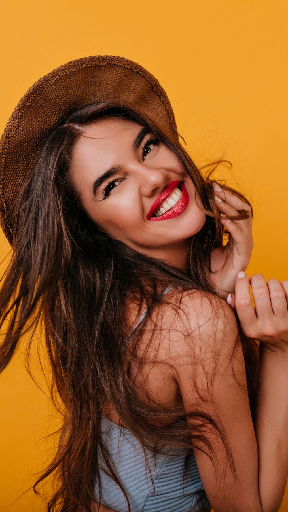 Glowmedik model wearing a straw hat against a orange background